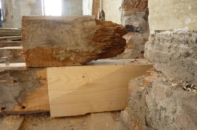 Ansicht einer ausgeführten Überblattung mit darüber liegendem originalem zerstörtem Holzbalkenkopf.